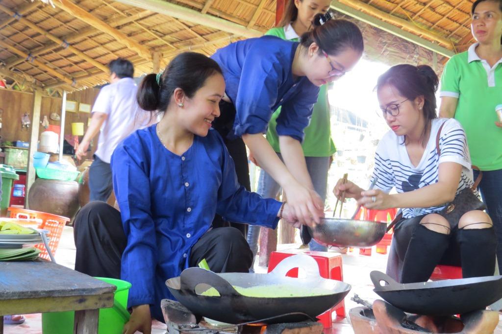 Các chị em phụ nữ và các đồng nghiệp nam hào hứng với các hoạt động dã ngoại như thi lột dừa khô, thi đổ bánh xèo dân gian, thi bắt cá